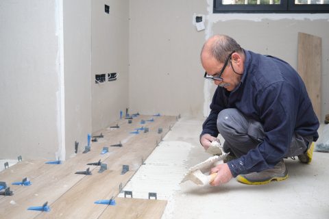 tiler putting tiles adhesive to the floor with the 2023 11 27 05 34 13 utc